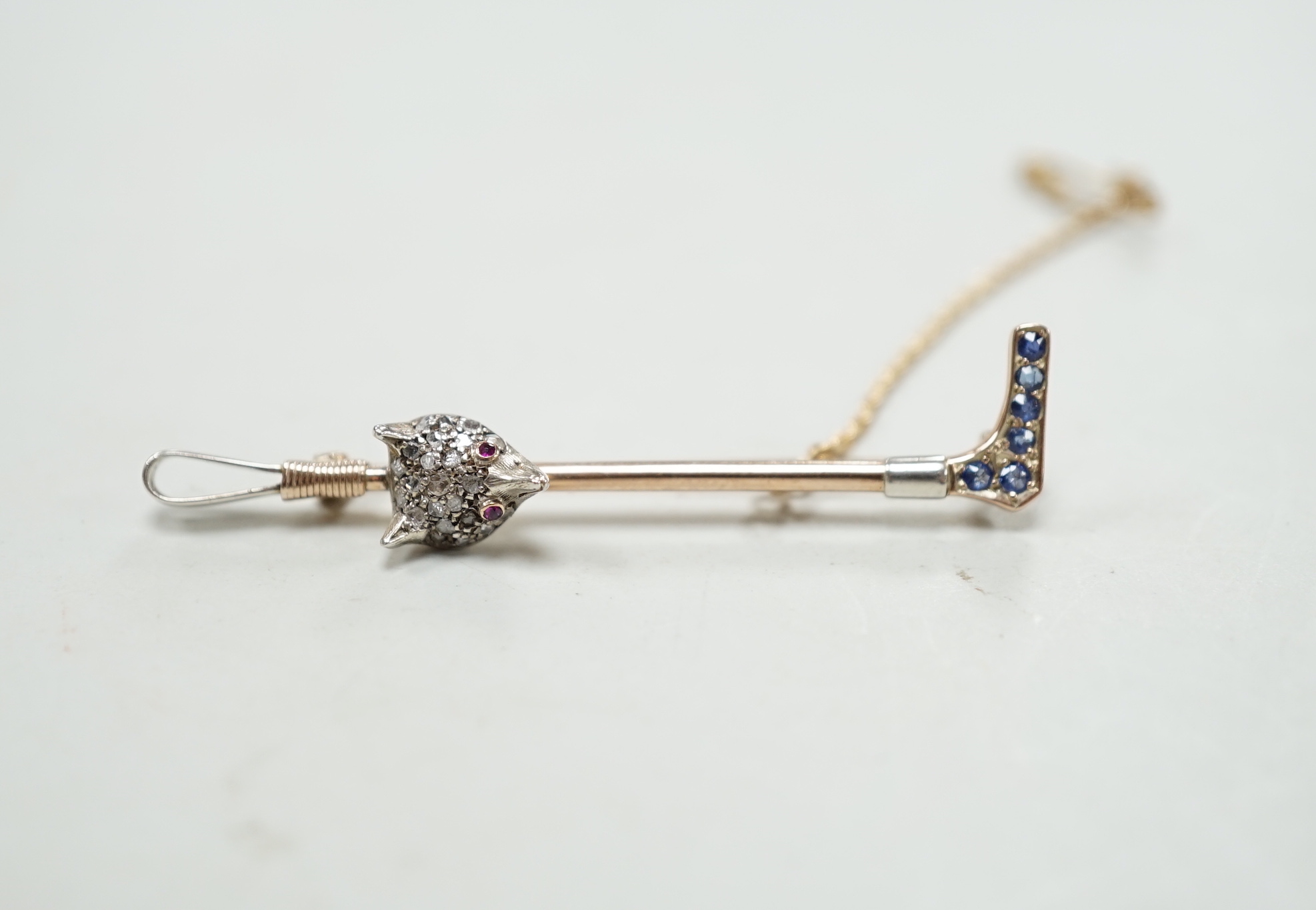 An Edwardian yellow metal, sapphire and diamond cluster fox head and riding crop bar brooch, with ruby set eyes, 52mm, gross weight 4.1 grams, in fitted box.